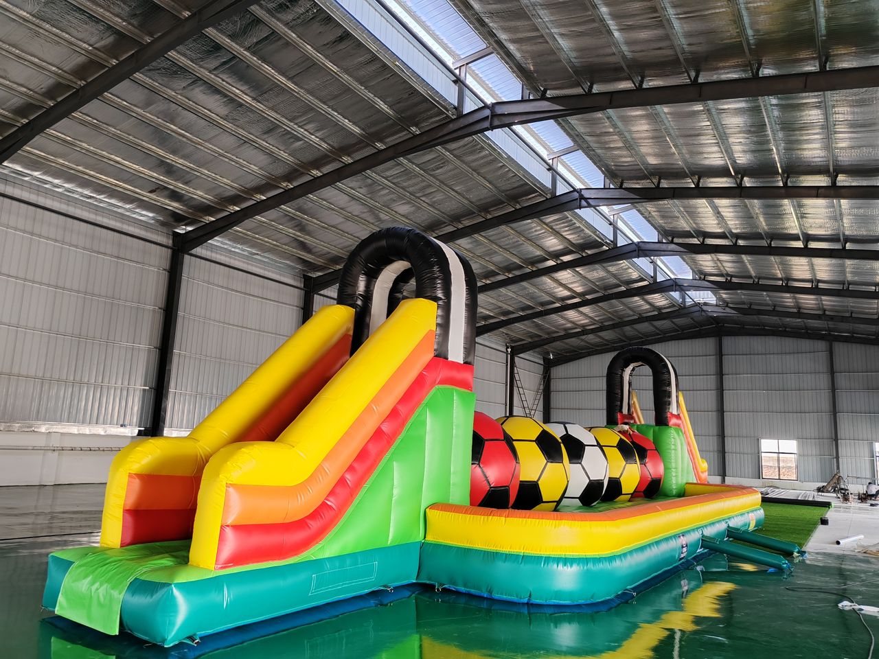 Football-themed inflatable challenge castle with slides and ball obstacles