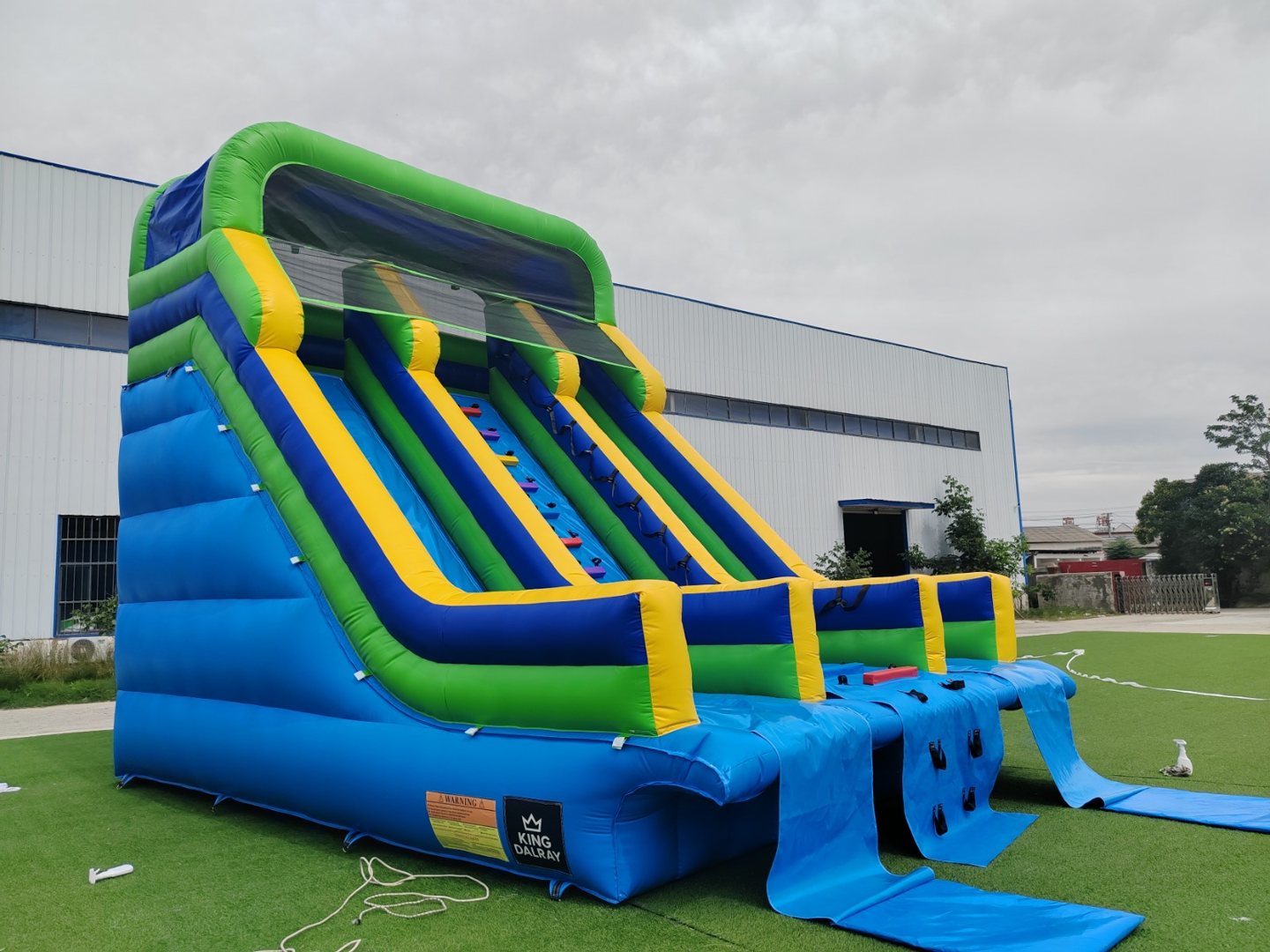 Tall blue, green and yellow inflatable water slide with multiple lanes