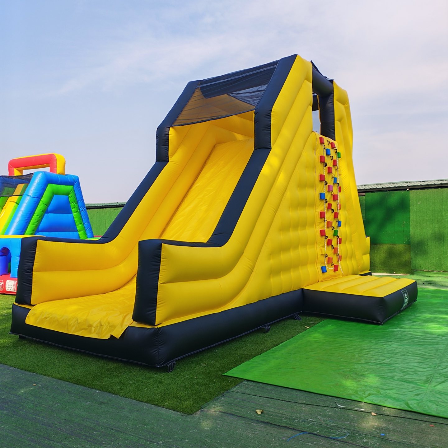 Angled view of the yellow climbing slide with a climbing wall